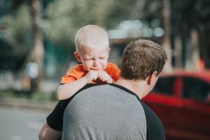 Child crying looking back as father takes him away
